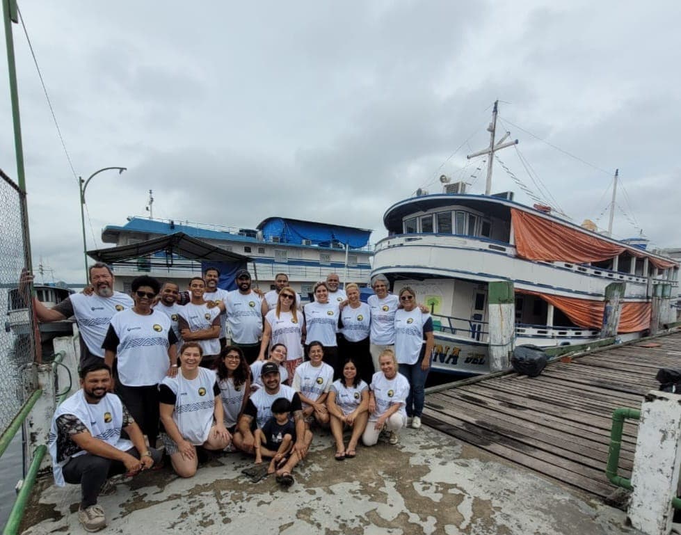 Equipe de voluntários reunida no píer junto ao barco